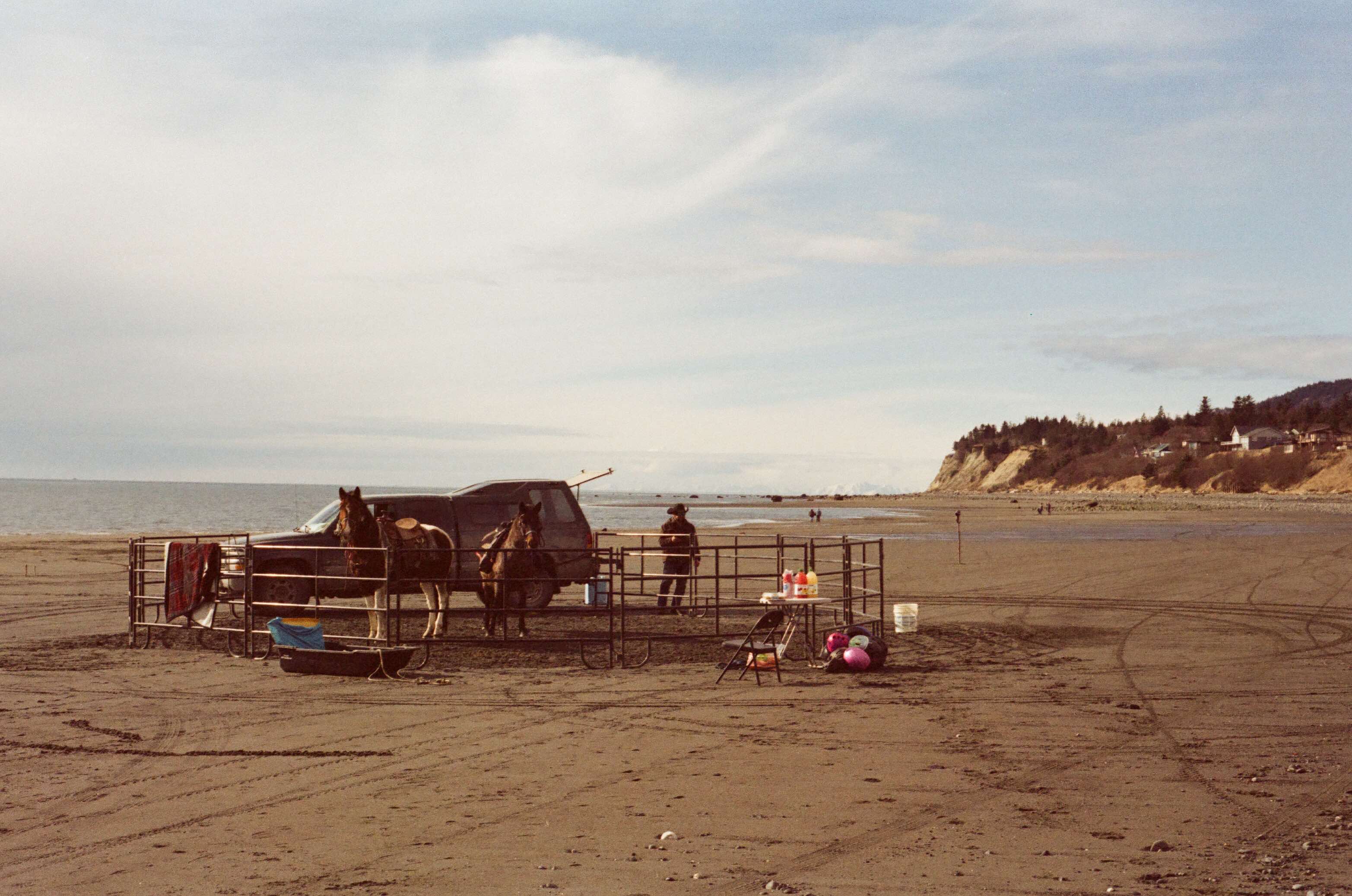 man stands next to an improvised stable on the beach