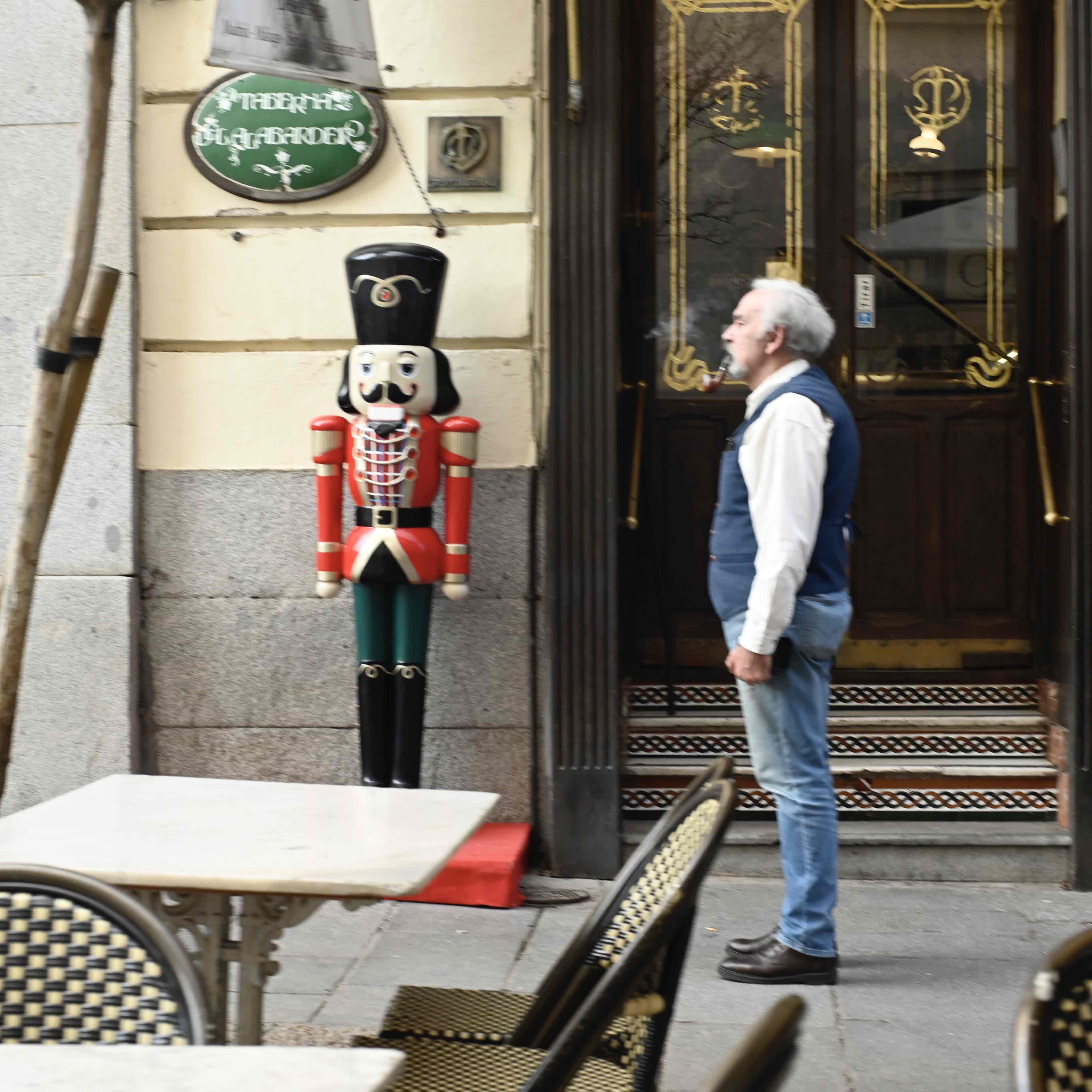 man stands next to a tall nutcracker