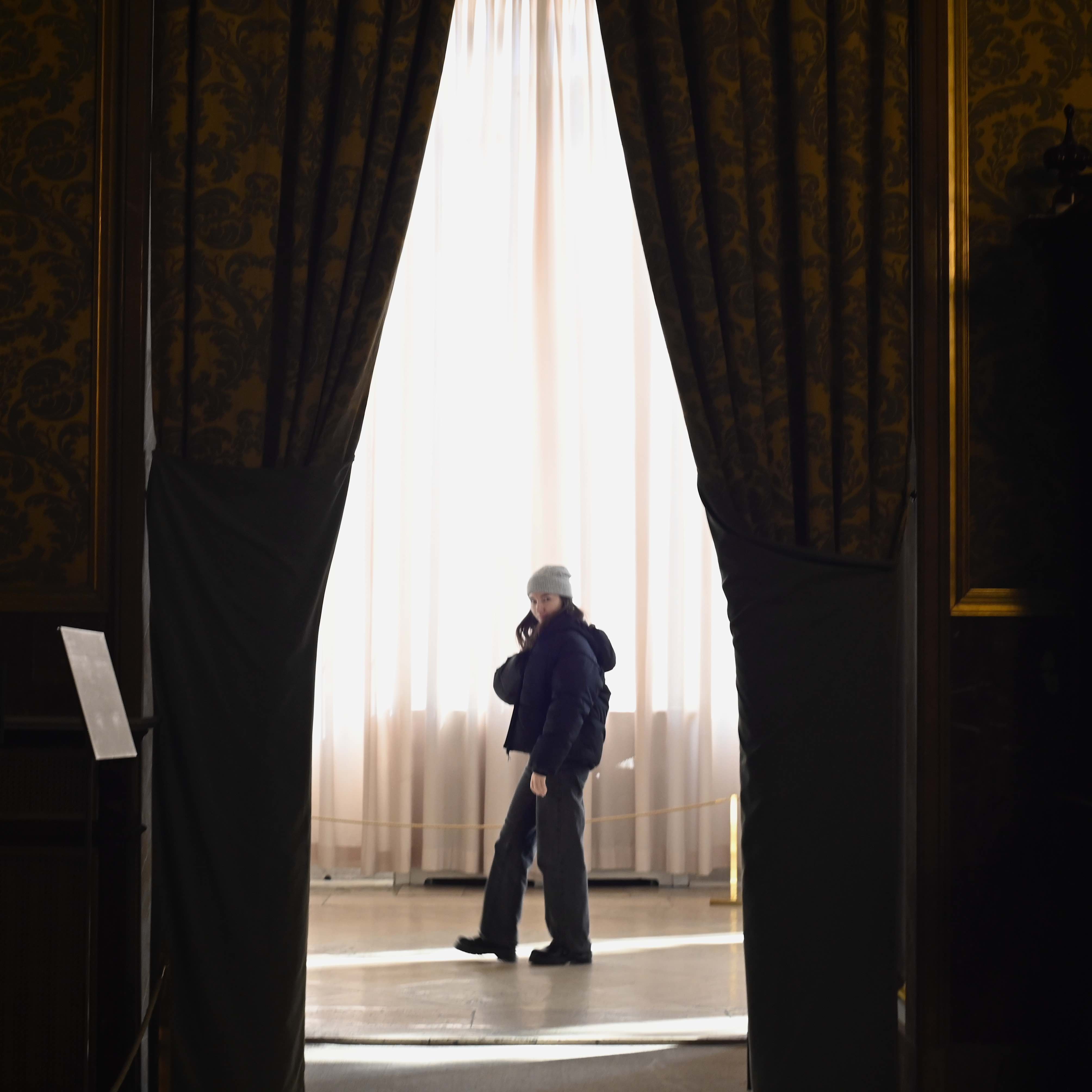 Woman walks in between 2 curtains