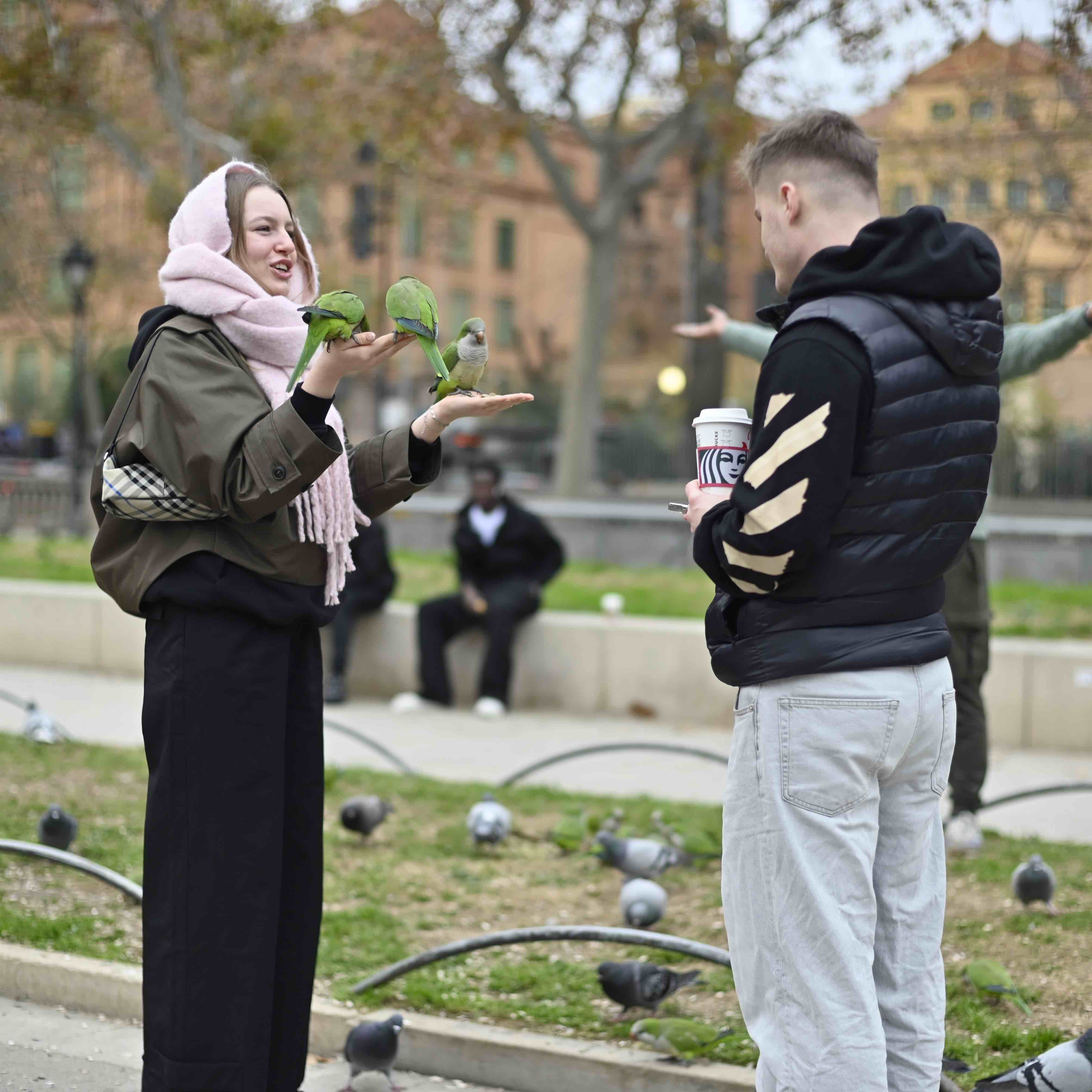 man looks at his partner holding up parakeets